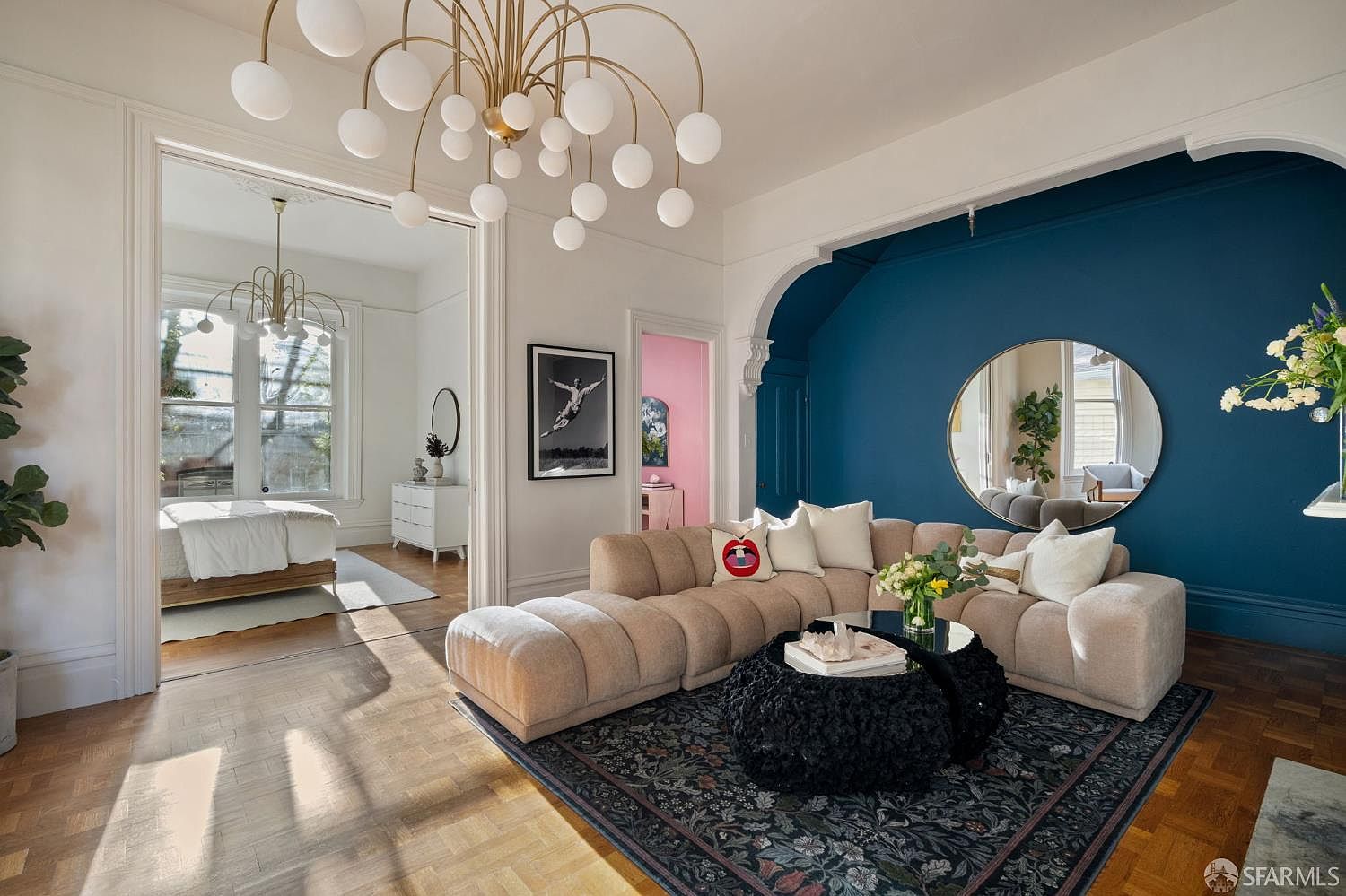 The grand living room with parquet floors, brass globe chandelier, and deep teal accent wall
