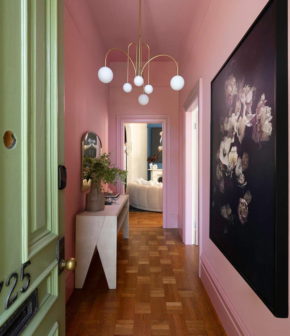 The rose-pink entry hall with parquet floors, brass chandelier, and the green sash door bearing house number 725