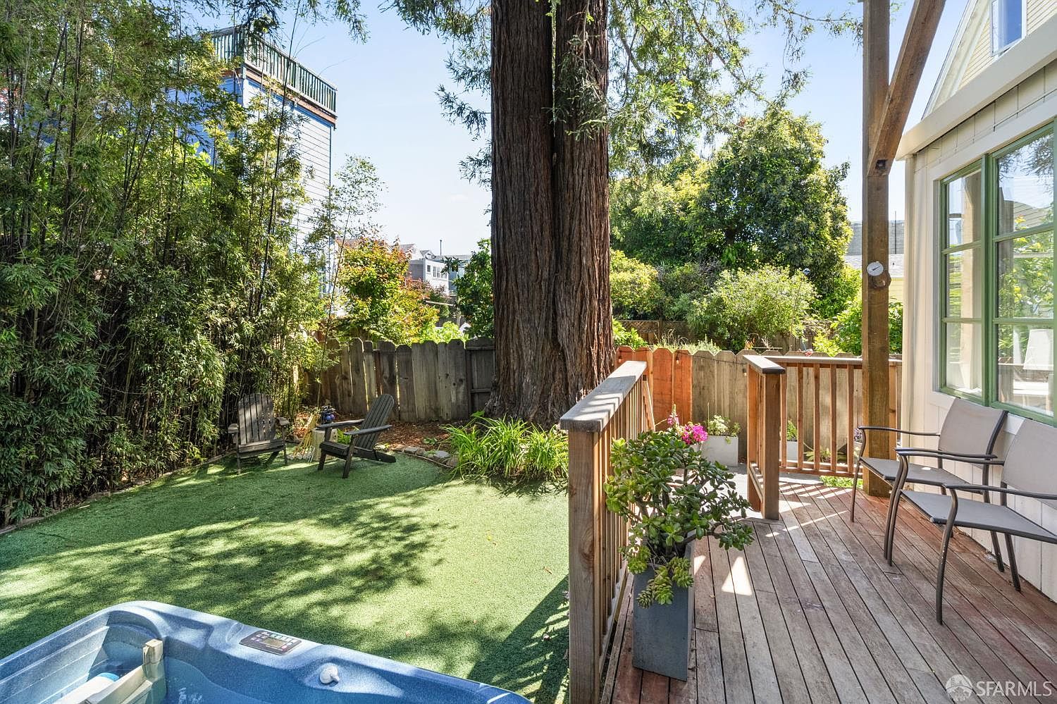 The private garden and patio beneath the towering redwood, with hot tub and exclusive-use outdoor space
