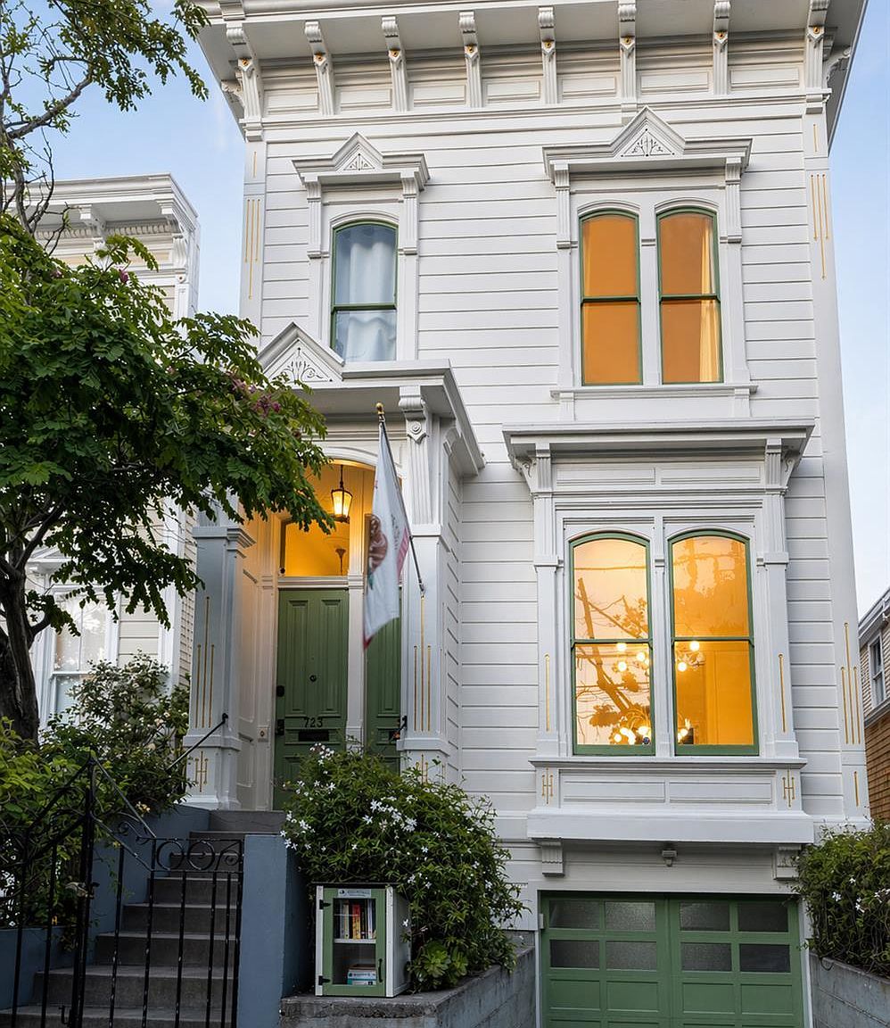 725 Shotwell Street at twilight, an Italianate Victorian with sage-green door and lit interior windows